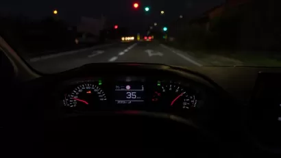 Close-up of car dashboard with speedometer at 35 on roadway at night.